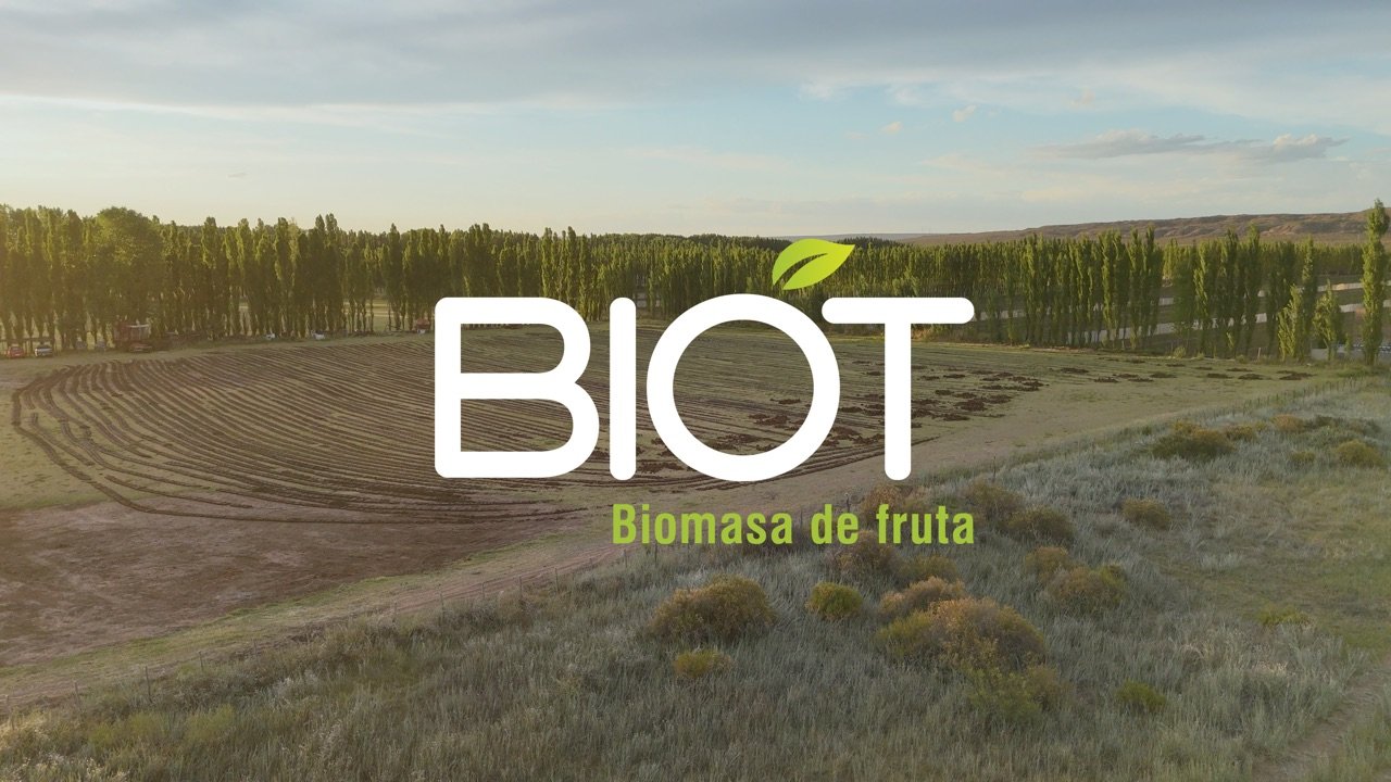 Vista aérea del campo de BIOT al atardecer, con el logotipo BIOT / Biomasa de fruta sobreimpreso